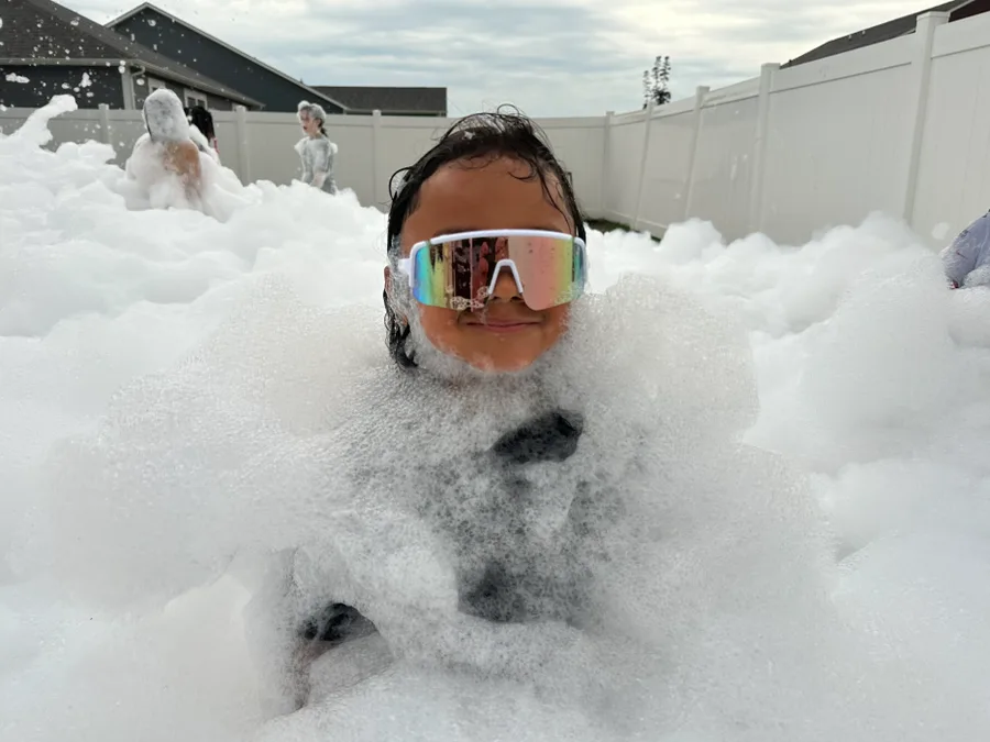 A kid covered in foam during a backyard birthday foam party