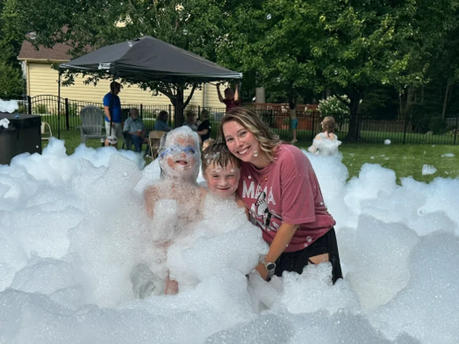 A parent and kids hugging in the foam at a birthday party