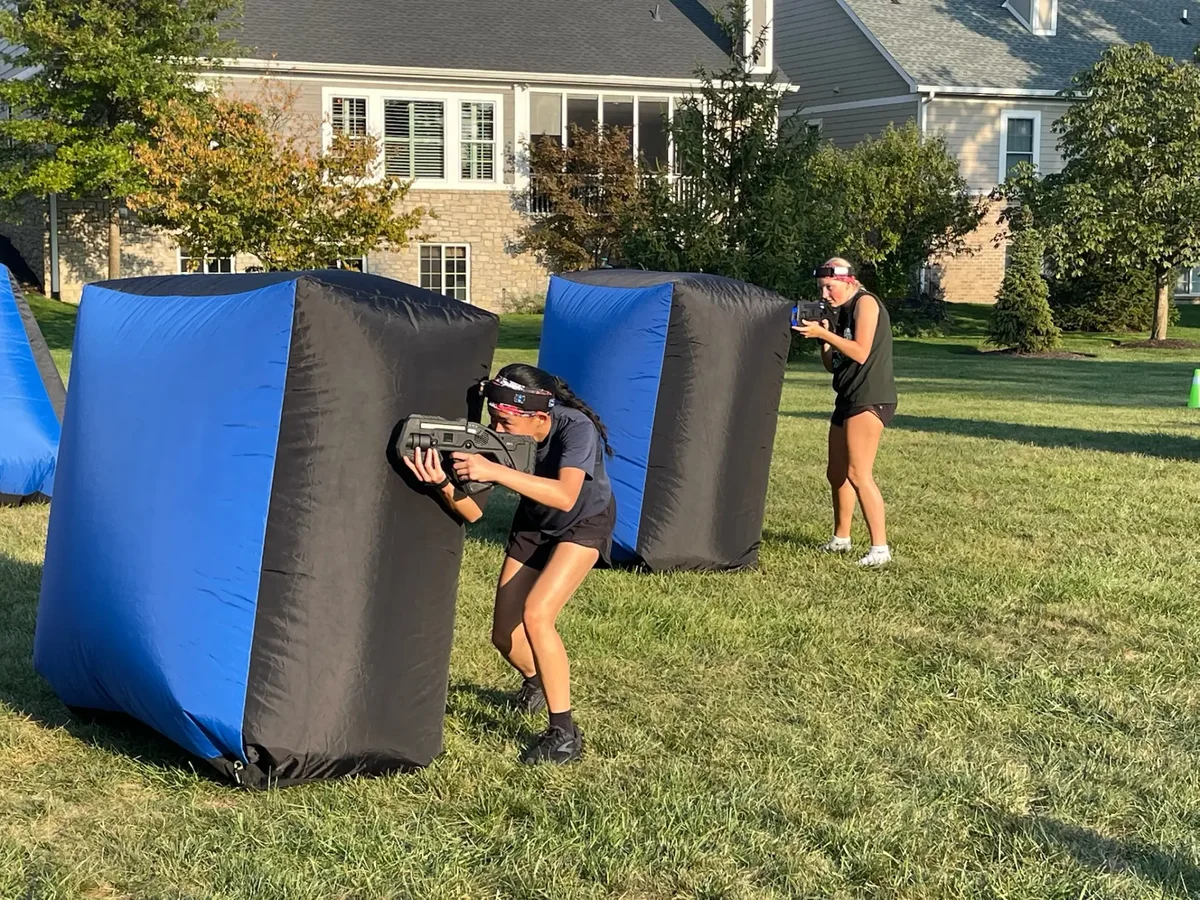 Girl aiming a Falcon LUX laser tag blaster during a birthday party