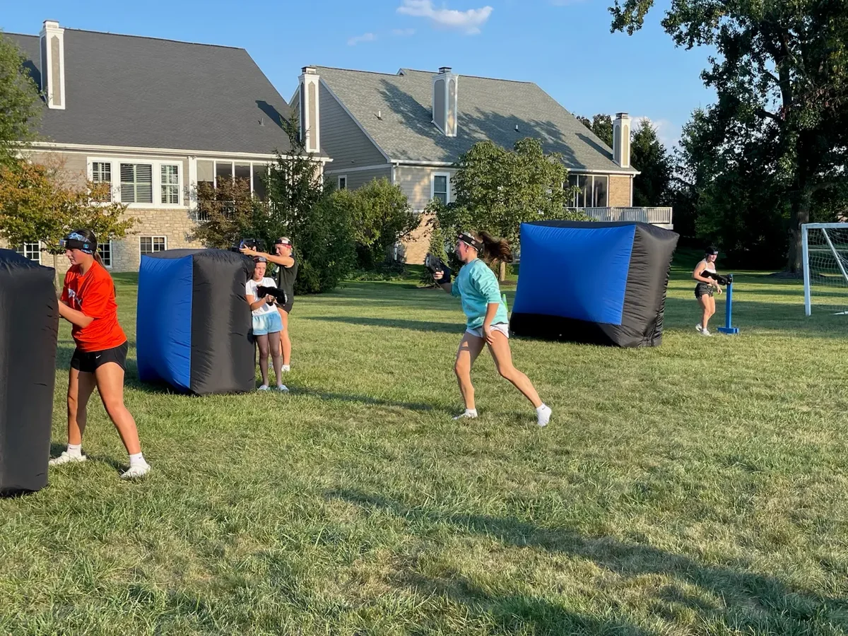 Kids running through an outdoor laser tag arena at a birthday party