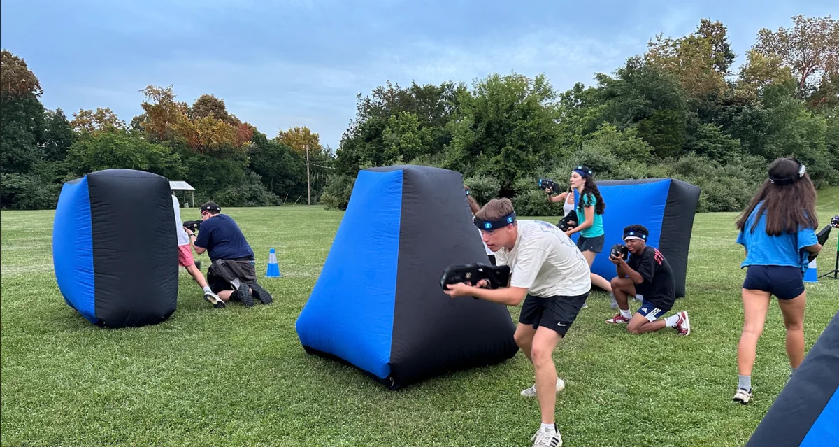 Camper sprinting past inflatable bunkers during an outdoor laser tag battle