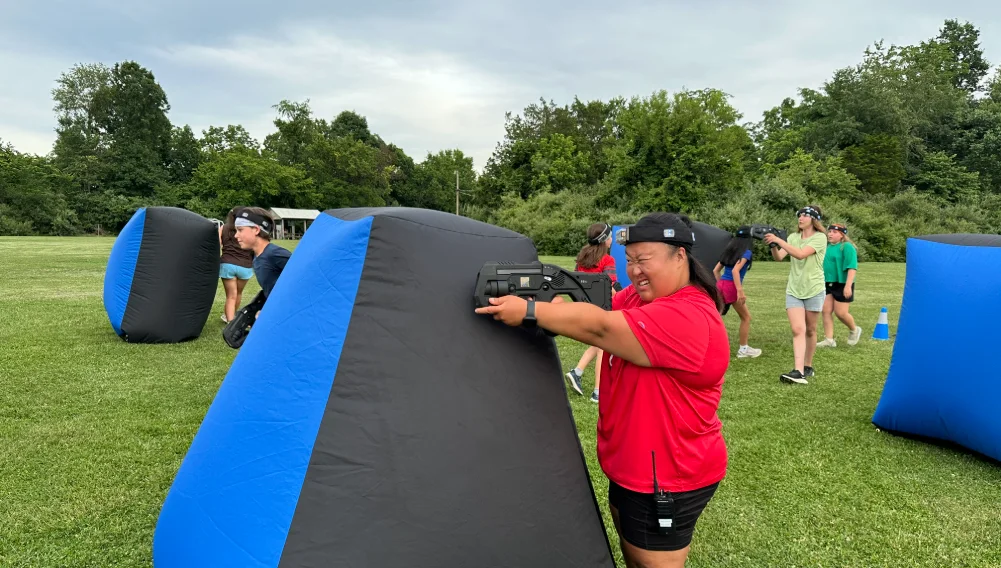 Camper taking cover behind an inflatable bunker during outdoor laser tag