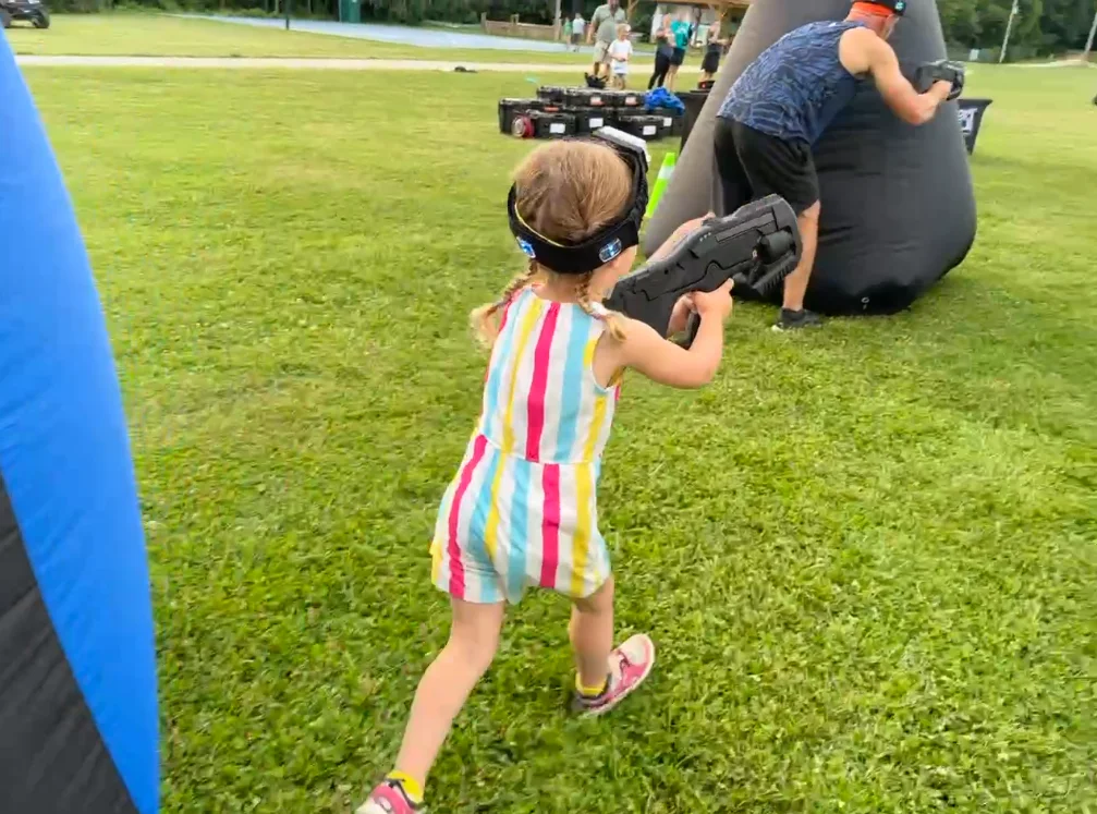 Young camper running toward the bunkers during an outdoor laser tag mission