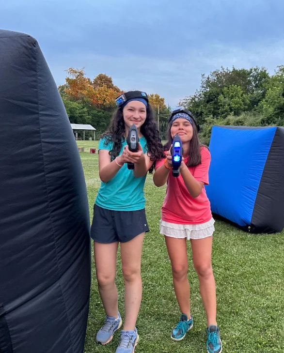 Two campers posing with laser tag blasters between the bunkers