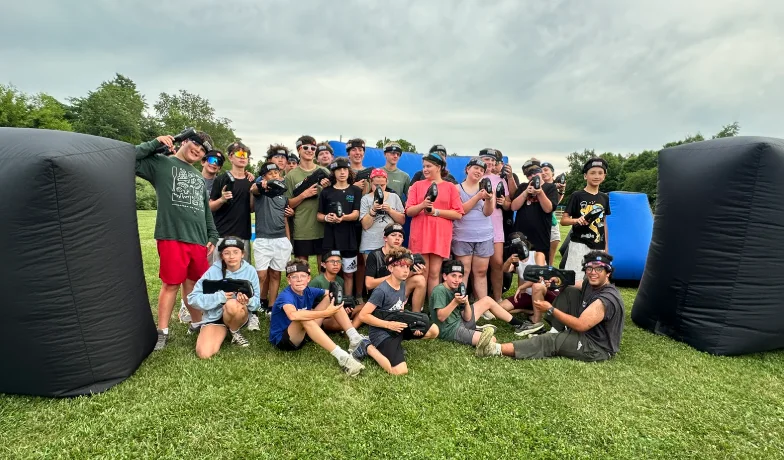 Large camp group photo between inflatable bunkers on the laser tag field