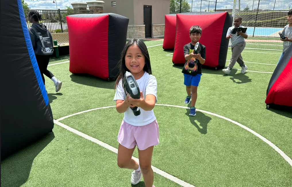 Camper running with a laser tag blaster during an outdoor summer camp mission