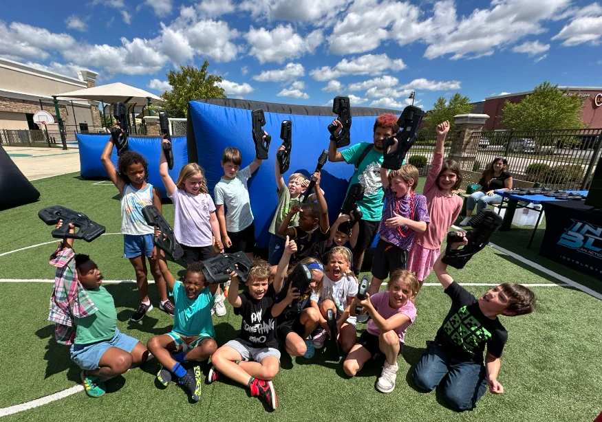 Camp group cheering with laser tag blasters raised after a mission