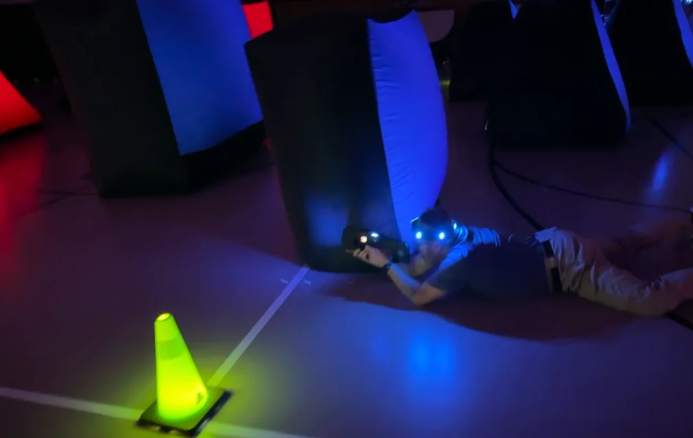 Team member aiming a laser tag blaster from a crouched position during a corporate team building event