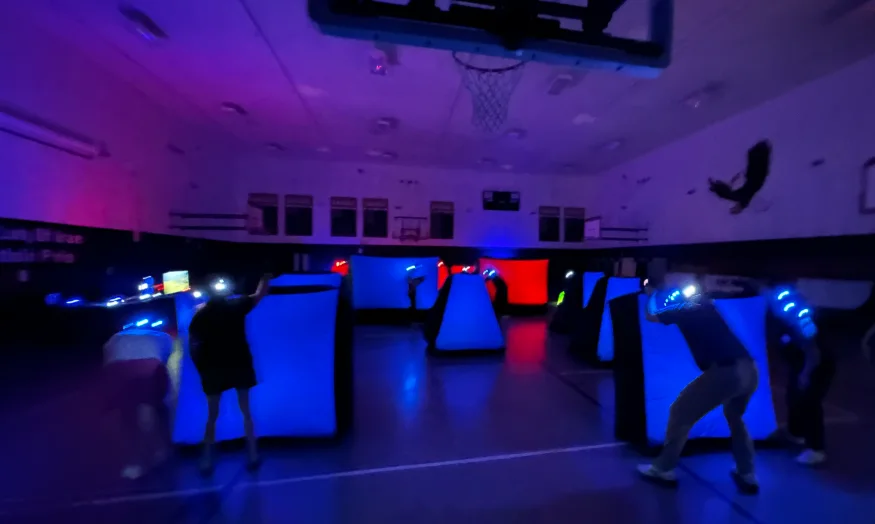 Full glow laser tag arena set up in a gymnasium for a corporate team building event