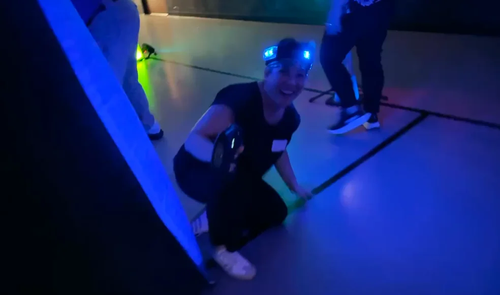 Team member taking cover behind a glowing blue bunker during a corporate laser tag event