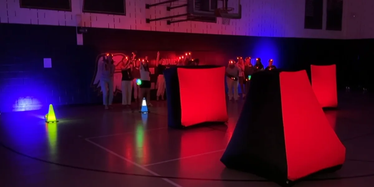 Group lined up along the wall with headlamps before a glow laser tag mission