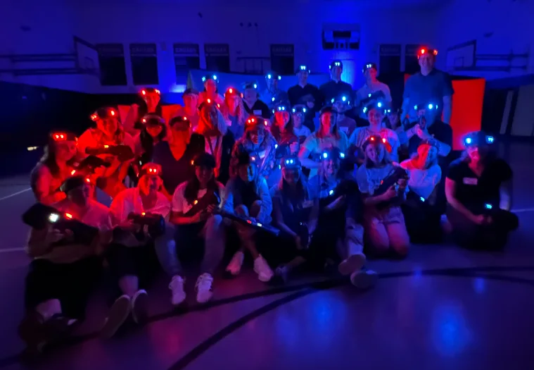 Large group photo with glowing headlamps after a community laser tag event