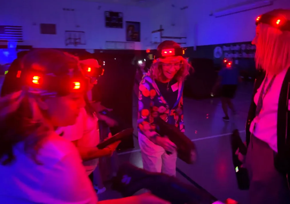 Group of teammates laughing together with headlamps on during a glow laser tag event