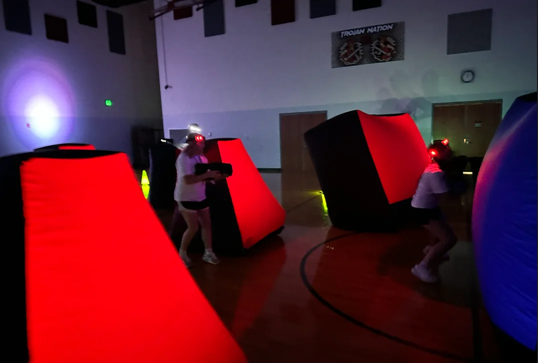 Students taking cover behind glowing inflatable bunkers during an After Prom laser tag mission