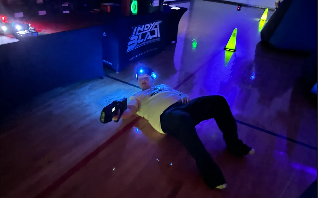 Student play-acting being tagged out on the gym floor next to the Indy Blast check-in table during After Prom