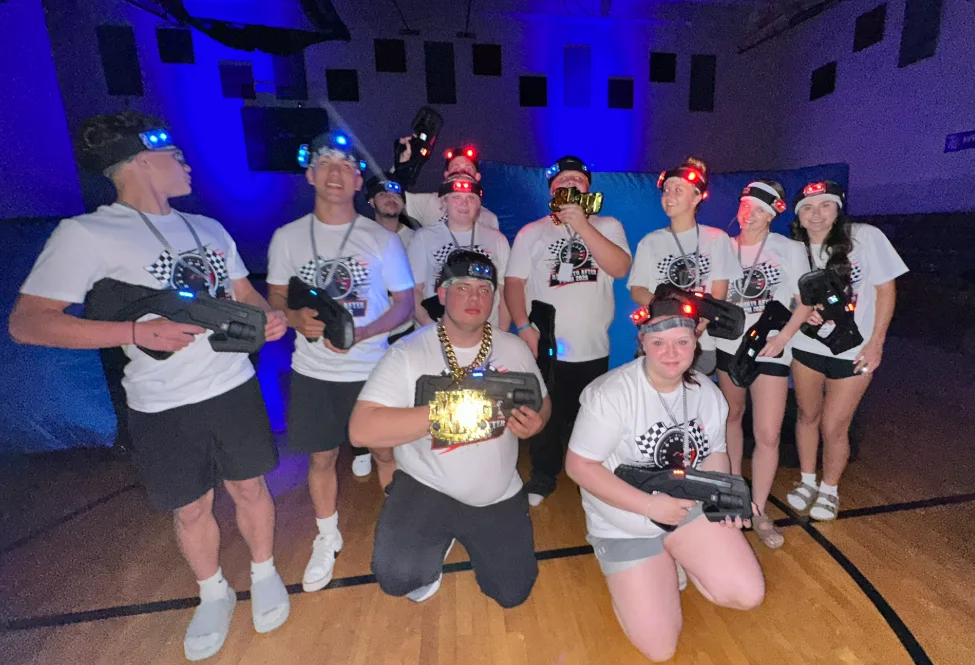 High school After Prom team posing with trophies and laser tag blasters after a glow-in-the-dark tournament