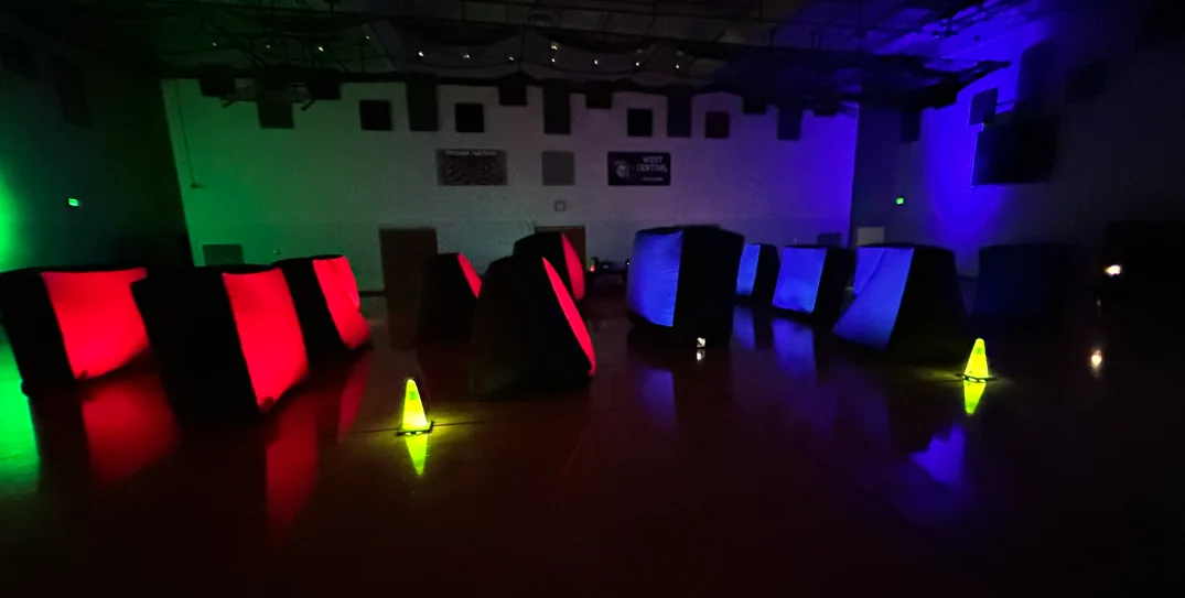 Glow-in-the-dark laser tag arena set up in a school gym for After Prom