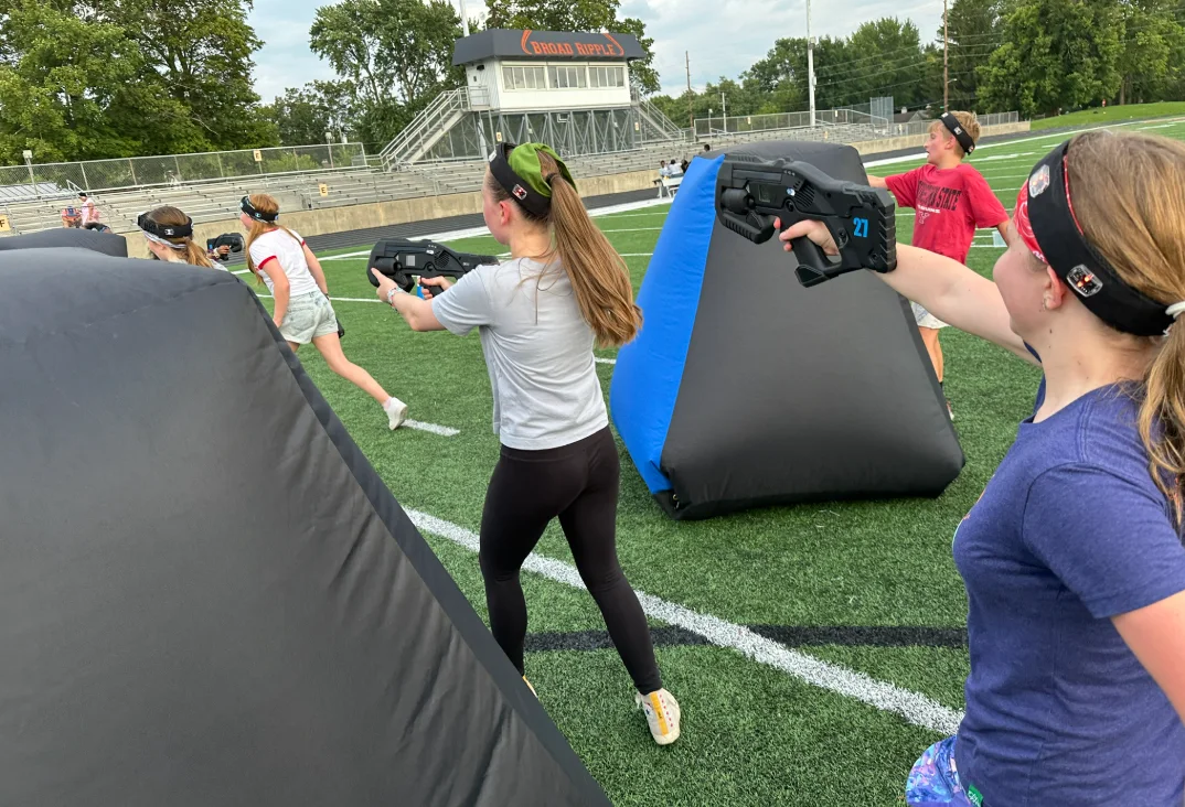 Students taking aim from behind bunkers with the Broad Ripple scoreboard in the background