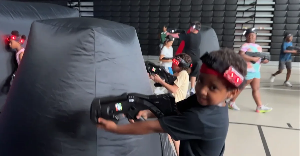 Elementary school student aiming a laser tag blaster from behind a bunker during Eastridge Elementary battles