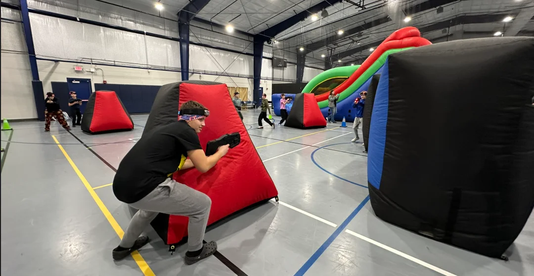 A team of students moving between bunkers during a middle school PTO laser tag fundraiser