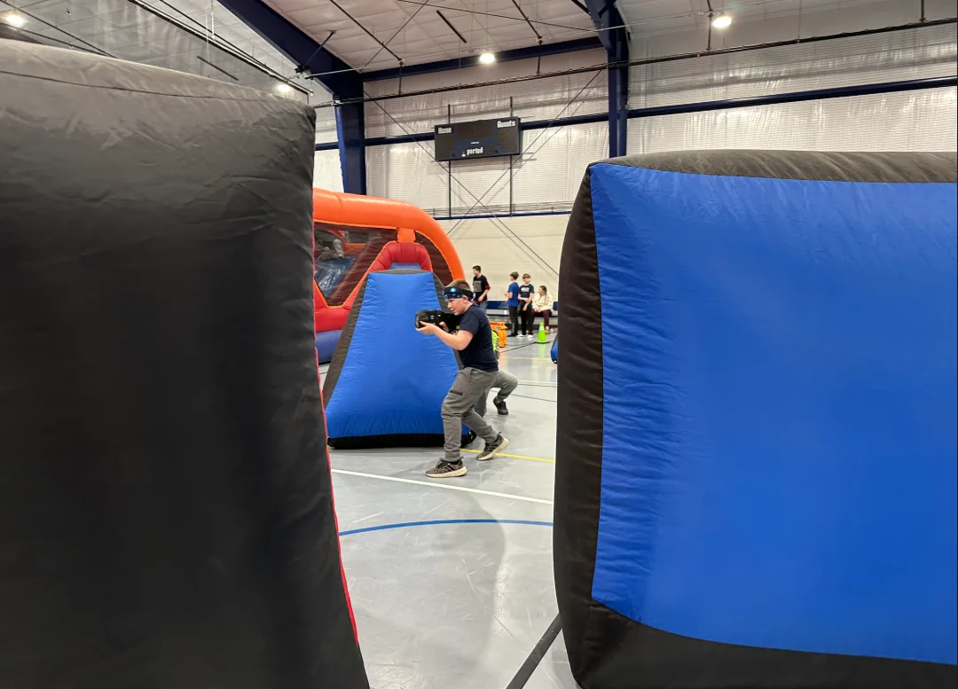View between inflatable bunkers of a student taking aim during a middle school laser tag fundraiser