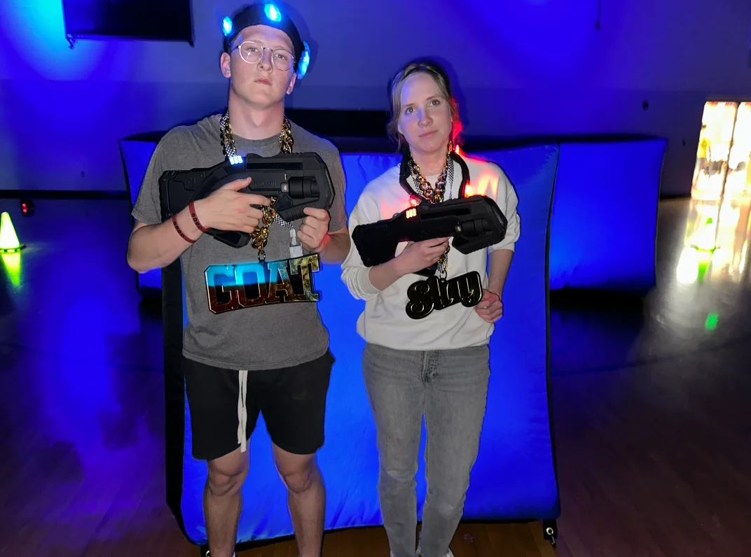 Students posing with laser tag blasters and glow gear after an After Prom laser tag event